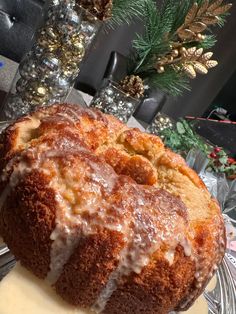 a bundt cake with icing sitting on top of a glass plate next to pine cones