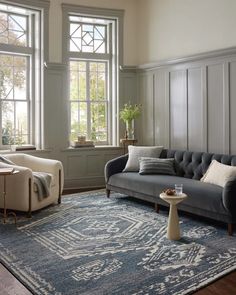 a living room with couches, chairs and rugs in front of two windows