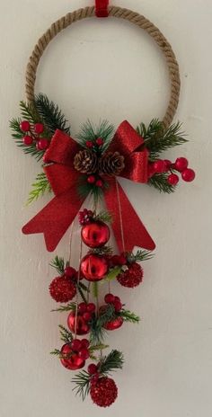 a christmas wreath hanging on the wall with pine cones and red berries attached to it