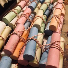 many different colored candles tied together on a wooden table next to other small ones with rope around them