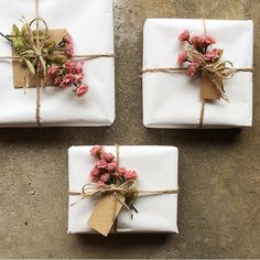 three wrapped presents tied with twine and decorated with pink flowers on top of each other