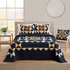 a black and gold quilted bed in a room with two chairs next to it