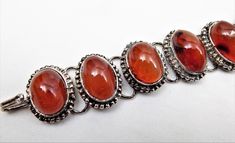 "Baltic Amber Bracelet, Oval Amber Cabochons, Silver Plate Metal, Hook Closure, Vintage Bracelet Bracelet measures 6 1/2\" long, 1\" wide, approximate. Gorgeous deep orange red cabochons, with some inclusions and beautiful spotting, Cut in oval shapes, Set in silver plate finish settings, beaded frames around each stone. Ribbed hinges linking each setting, articulating, then a fish hook closure. Deep rich color on the stones, nice work. There is a stone in the middle that has a creative flaw, ri Traditional Amber Oval Jewelry, Classic Oval Baltic Amber Jewelry, Classic Amber Oval Cabochon Jewelry, Adjustable Oval Cabochon Bracelet, Vintage Amber Oval Beads Jewelry, Silver Baltic Amber Oval Jewelry, Bead Frame, Vintage Jewelry Sets, Chunky Chain Necklaces