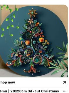 a christmas tree made out of paper on top of a blue circle with green leaves