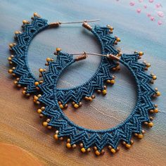 a pair of blue and yellow beaded hoop earrings on top of a piece of fabric