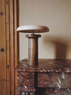 a table with a lamp on top of it next to a wooden cabinet and door