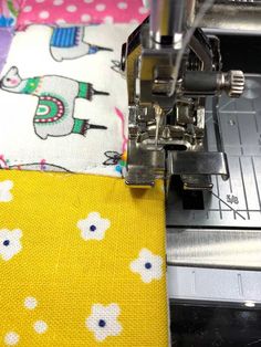 the sewing machine is working on the yellow and white fabric that has been sewn