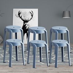 six blue stools sitting in front of a gray wall with a deer painting on it