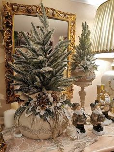 a christmas tree in a pot on a table next to other ornaments and candles with a mirror behind it