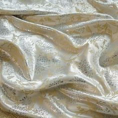 a close up view of a white and gold fabric with floral designs on the side