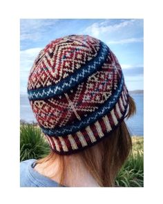 a woman wearing a knitted hat looking out at the ocean from behind her head