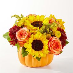 a pumpkin vase filled with sunflowers, roses and other flowers on a white background