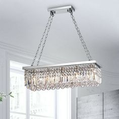 a crystal chandelier hanging from the ceiling in a room with white walls and windows