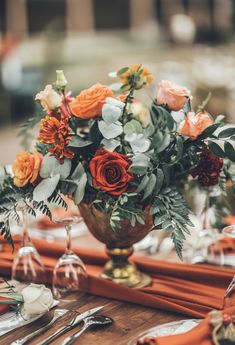 a vase filled with flowers sitting on top of a wooden table next to silverware