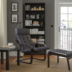 a chair and ottoman in front of a bookshelf with pictures on the wall