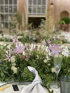 the table is set with flowers and greenery