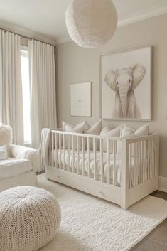 a baby's room with an elephant print on the wall and white bedding