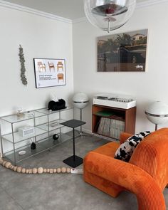 an orange chair sitting in a living room next to a shelf filled with record records