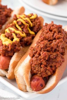 two chili dogs on buns with mustard and ketchup