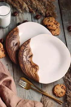 two white plates with cookies on them next to a glass of milk and some wheat