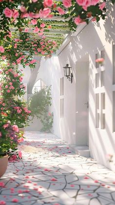 pink flowers growing on the side of a white building with an arched walkway leading to it