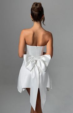 the back of a woman's white dress with a large bow