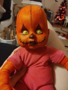 an orange doll with green eyes sitting on a chair