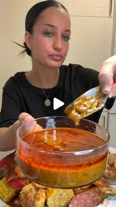 a woman eating soup from a bowl on top of a table