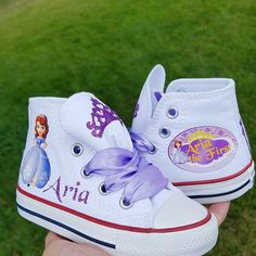 "I can do these in pink Converse if desired, just put that in the notes to seller box during check out. These Converse adorable! Each tongue has a lavender glitter crown, the right shoe has Sofia and your little one's name in glittery purple. The left shoe will come as shown but with your daughter's name and then \"the First\". Lavender double faced satin ribbon ties. If you want silver or gold crystals on the toes, please select that option during check out." Purple Canvas Shoes With Rubber Sole And Round Toe, Purple Canvas Shoes With Round Toe And Rubber Sole, Glitter Crown, Gold Crystals, Pink Converse, Custom Converse, Sofia The First, Shoes Custom, Girls Sneakers