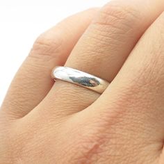 a person's hand with a silver ring on their left hand, wearing a white gold band