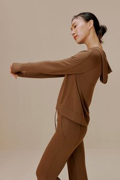 a woman in brown is stretching her arms