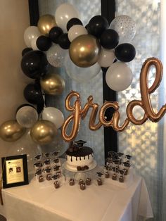 a table that has some balloons and cake on it with the word grace spelled out