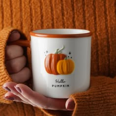 a woman holding a coffee mug with pumpkins on it