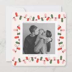 a christmas card with an image of two people kissing and lights around the frame on it