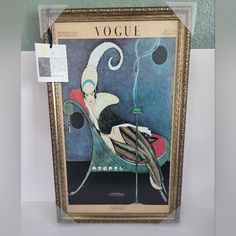 a painting hanging on the wall in front of a white wall with a sign that says voge