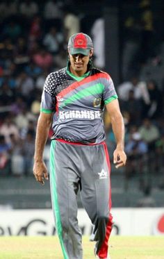 a man walking on top of a field wearing a green and red uniform with an american flag on it