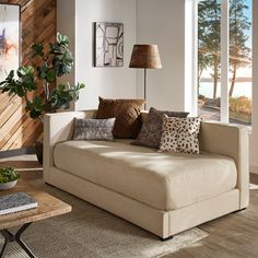 a living room filled with lots of furniture and pillows on top of a wooden floor