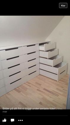 an empty room with white drawers on the floor and a wooden floor in front of it