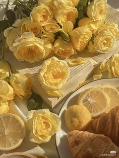 lemons, croissants and flowers on a table with an open book