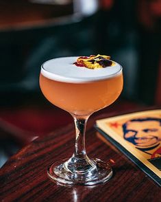 a drink sitting on top of a wooden table next to a framed photo in a restaurant