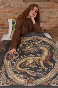 a woman sitting on top of a bed next to a dragon blanket