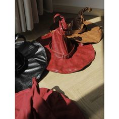 a red hat sitting on top of a wooden floor next to other hats and purses