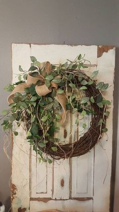 an old door with a wreath on it and a measuring tape in front of it