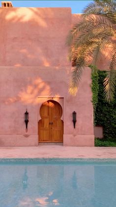 a house with a pool in front of it and palm trees around the entrance door