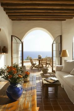 a living room with an arched doorway leading to the patio and dining area that overlooks the ocean