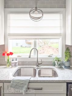 a kitchen sink under a window next to a counter top with flowers in vases