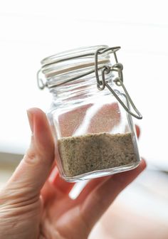 a hand holding a jar filled with sand