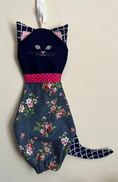 a black cat swimsuit hanging on the wall next to a toothbrush holder with pink and blue flowers