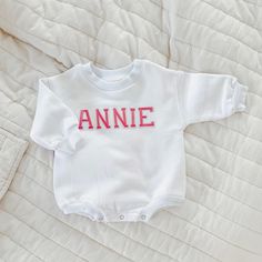 "Celebrate your sweetie with this piece featuring a pink embroidered lettered text on a white colored baby sweatshirt romper. This sweet piece is the perfect romper for baby. The design is printed a on 100% cotton fabric on, sturdy sweatshirt material. It is cozy soft and perfect for staying cuddly. This romper is oversized in style in a baby sweatshirt bubble romper design. Select the words you would like in the \"personlization\" section. Your word of choice must be under 6 in order to fit acr White Long Sleeve Tops For Baptism, White Sweatshirt With Name Print For Birthday, Cute White Embroidered Sweatshirt, White Embroidered Tops For Birthday, White Long Sleeve Tops For Gender Reveal, Cute White Top With Embroidered Logo, Cute White Tops With Embroidered Logo, White Long Sleeve Tops For First Birthday, Cute White Tops With Letter Embroidery