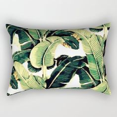 a banana tree print rectangular pillow on a white background with green and yellow leaves in the foreground